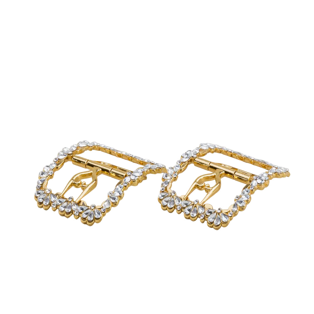 A pair of gold-tone buckle-style earrings embellished with clear rhinestones, displayed on a light off-white background.